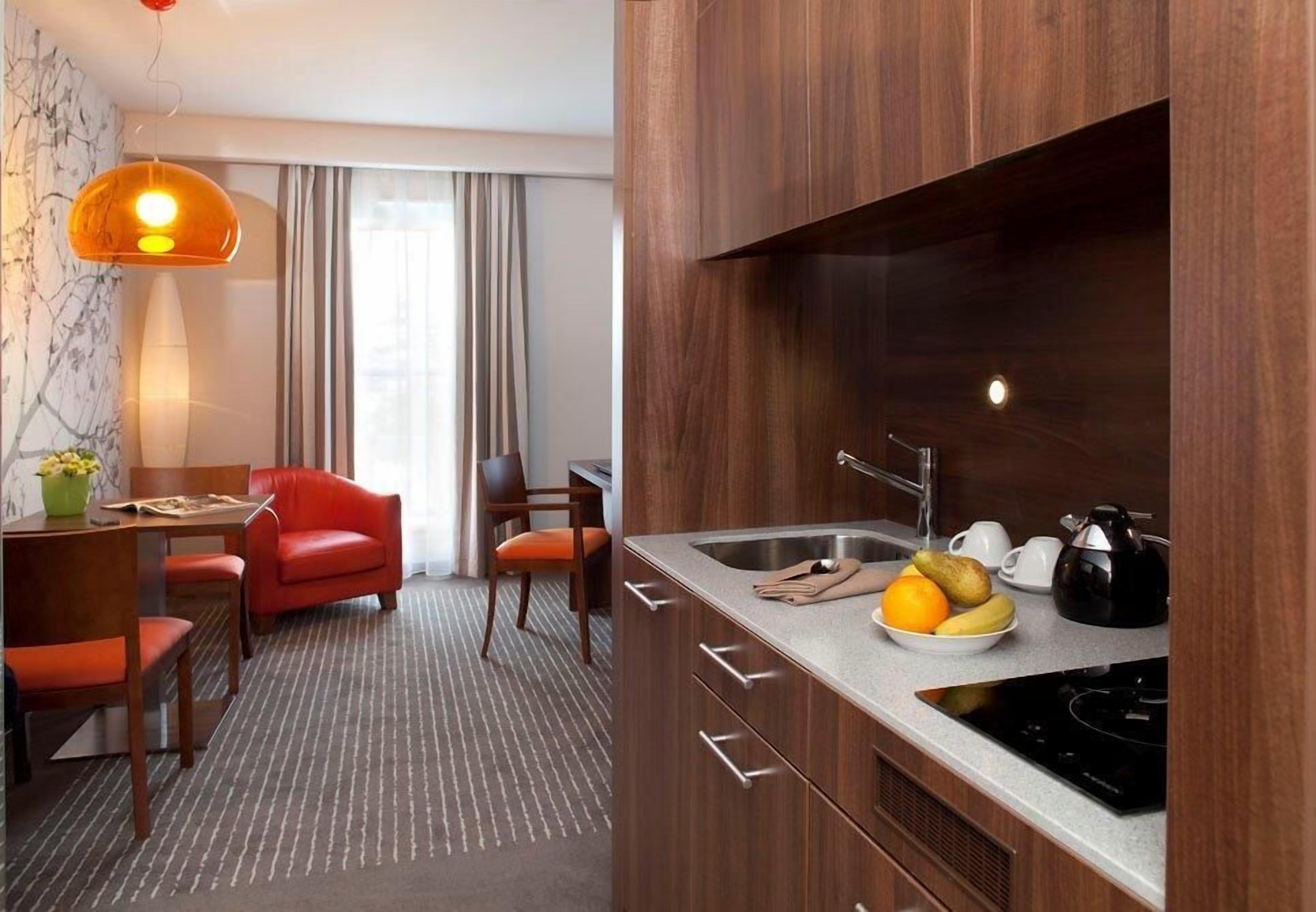 Una cocina moderna con estufa integrada, un fregadero y un comedor con una silla roja y una mesa.