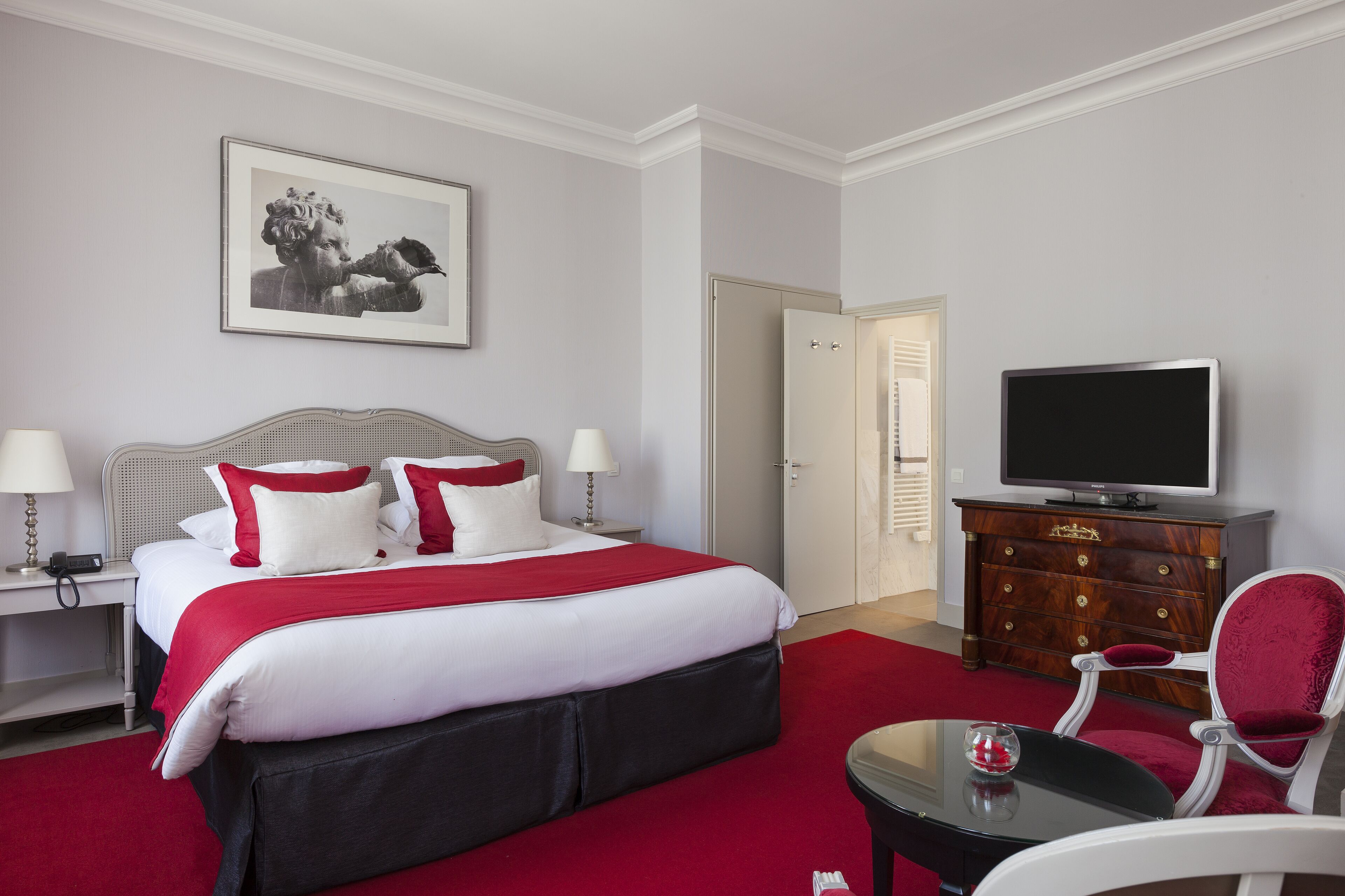 Een hotelkamer met een groot bed, een televisie, een kaptafel en een stoel.