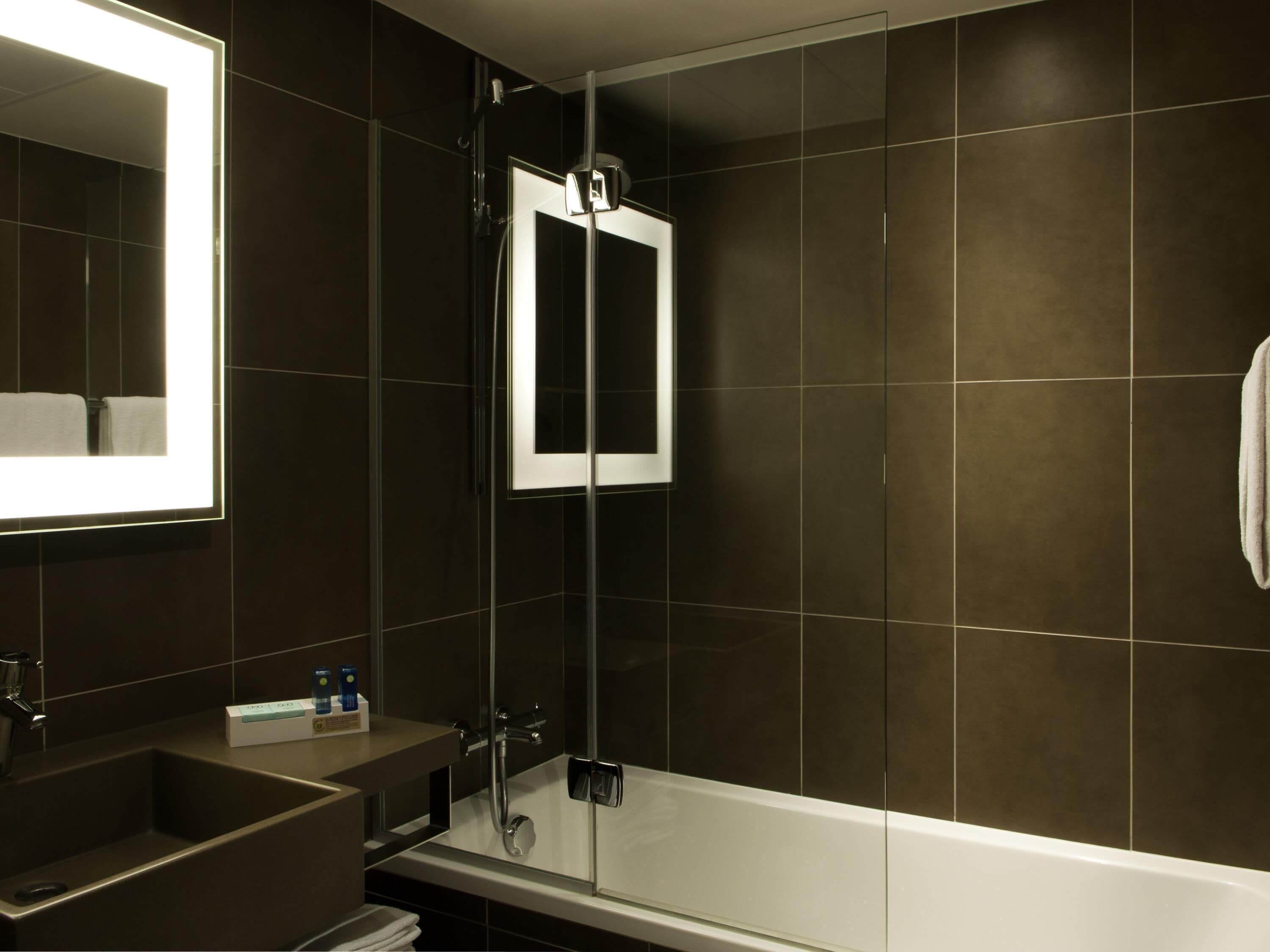 Un bagno moderno con doccia vetrata, un ampio specchio e una vasca da bagno bianca.