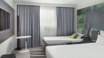 Une chambre d’hôtel moderne équipée d’un grand lit, d’un lit plus petit, d’un bureau et d’une télévision.
