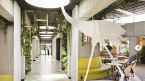 A modern interior with a central walkway, green plants, and a distinctive white sculpture. - Novotel Paris Charles de Gaulle Airport (Tremblay-en-France)
