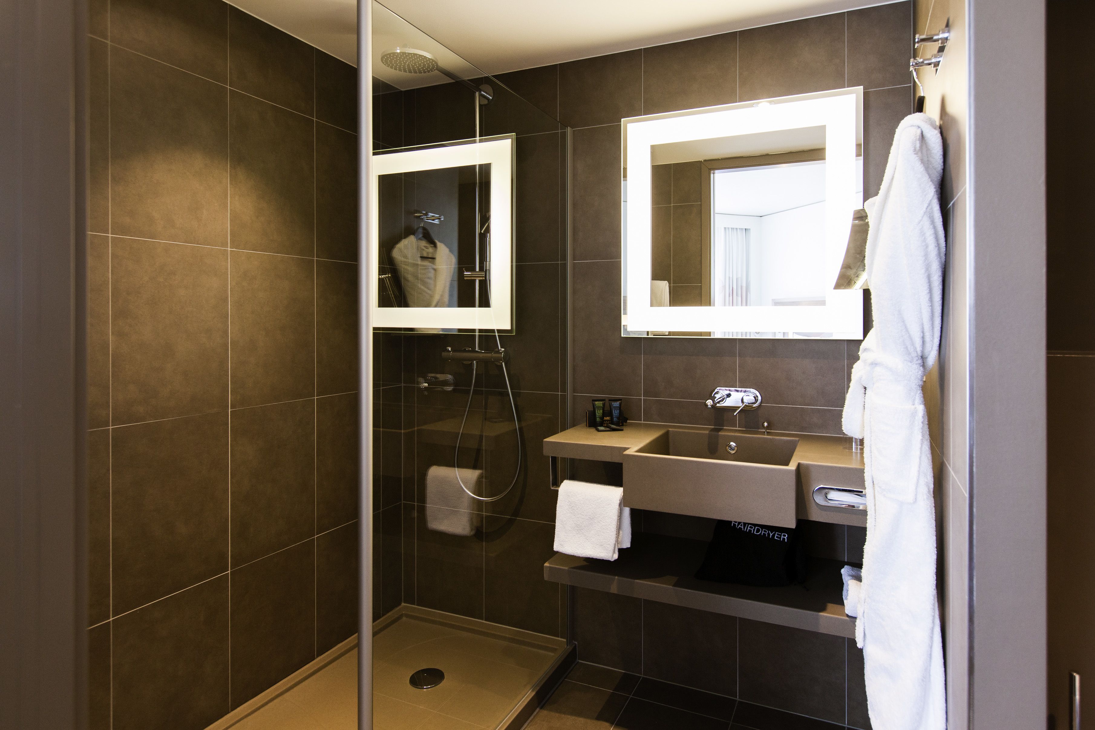 A modern bathroom with a walk-in shower, a vanity with a mirror, and a hairdryer.