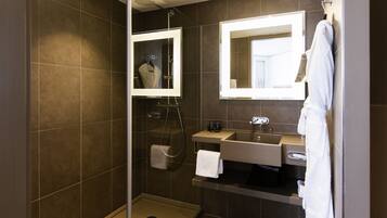 A modern bathroom with a walk-in shower, a vanity with a mirror, and a hairdryer.