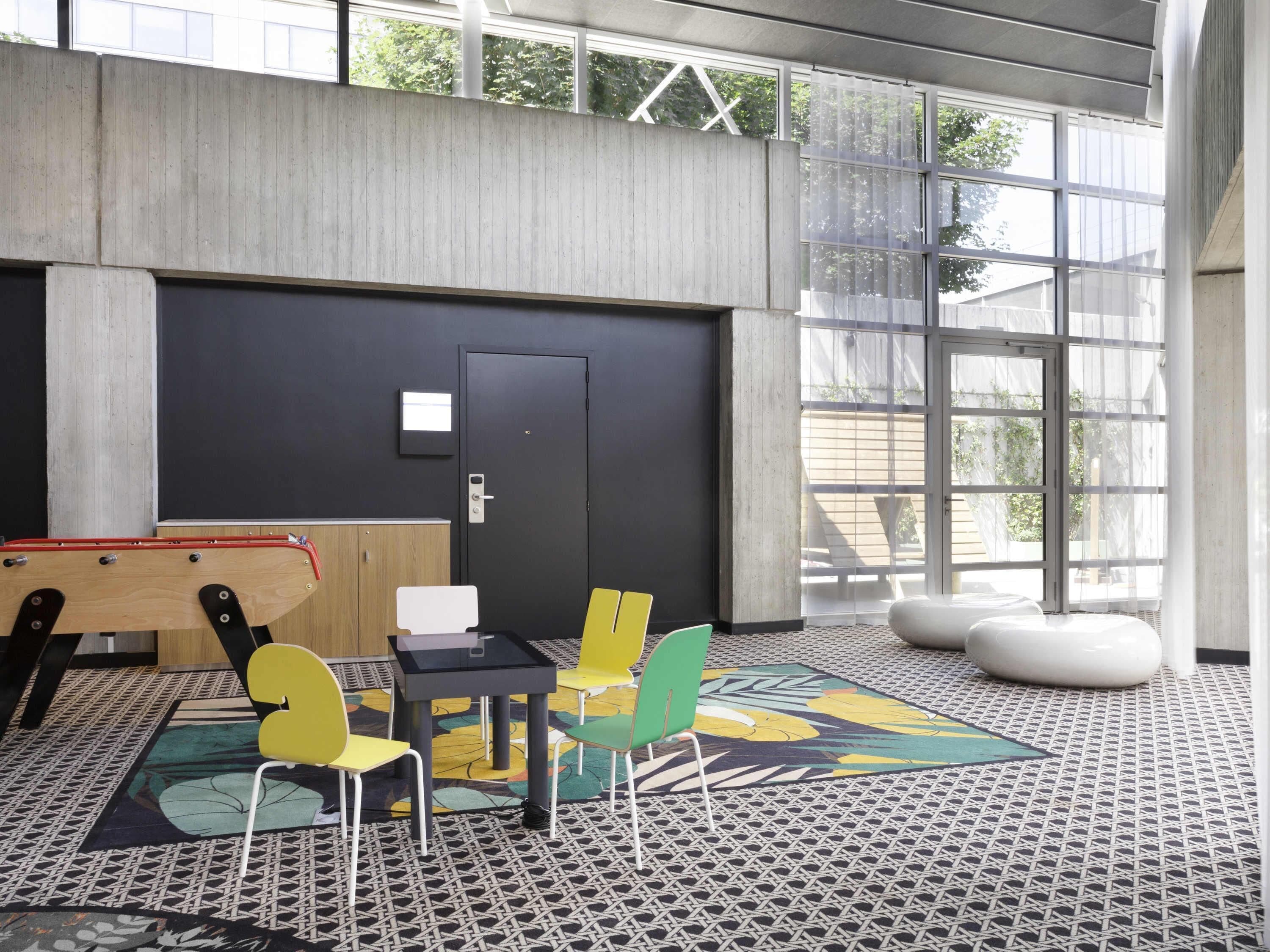 A modern interior with a black door, a small table with chairs, and a large window.