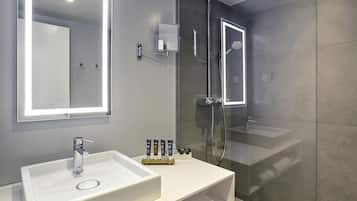 A modern bathroom with a large mirror, a white sink, and a glass-enclosed shower.