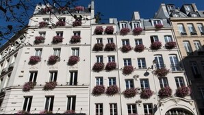 A multi-story building with balconies adorned with flowers. - Relais Saint Germain (Paris)