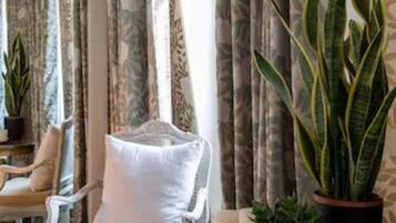Una habitación con una mesa redonda de madera, una silla blanca acolchada y una planta en maceta.