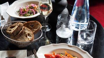 Una mesa de comedor con una variedad de platos, incluyendo una ensalada, pan y un postre con fresas. También hay vasos y una botella sobre la mesa.