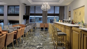 Un vestíbulo de hotel con zona de bar, asientos y ventanas amplias.