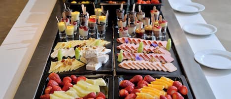 A buffet with various food items including fruits, cheeses, and meats.