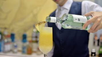 A bartender pouring a drink into a glass with a pineapple garnish.