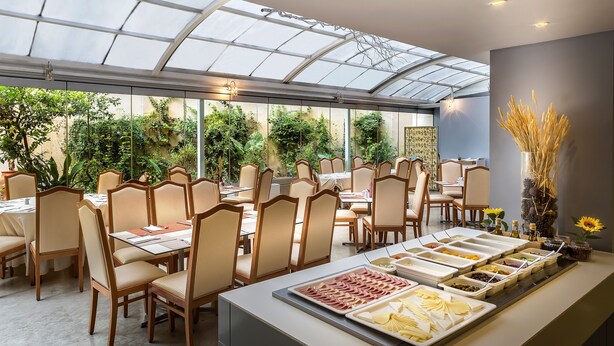 Un restaurante con techo de vidrio, sillas de madera y un bufé con diversas opciones de comida.