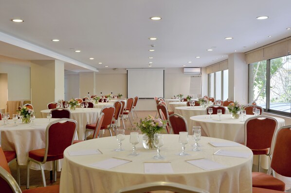 A conference room with multiple round tables, each set with chairs, documents, and floral centerpieces.