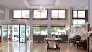 Un vestíbulo espacioso con candelabro, ventanas amplias y zonas de estar.