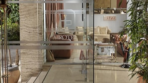 Un vestíbulo de hotel con diseño moderno, que incluye un mostrador de recepción, asientos cómodos y una planta grande en maceta.