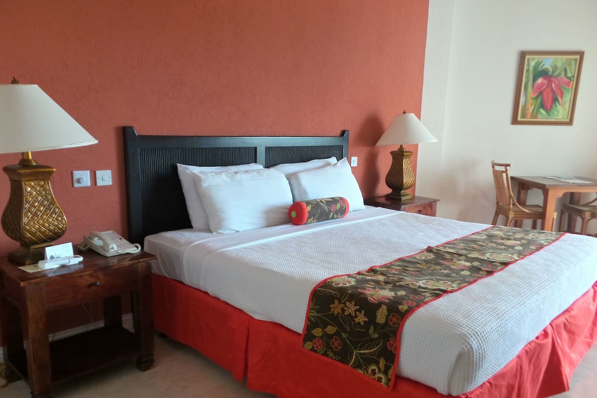 A neatly made bed with white linens and a floral-patterned bedspread, flanked by two bedside tables with lamps, a telephone, and a small card.