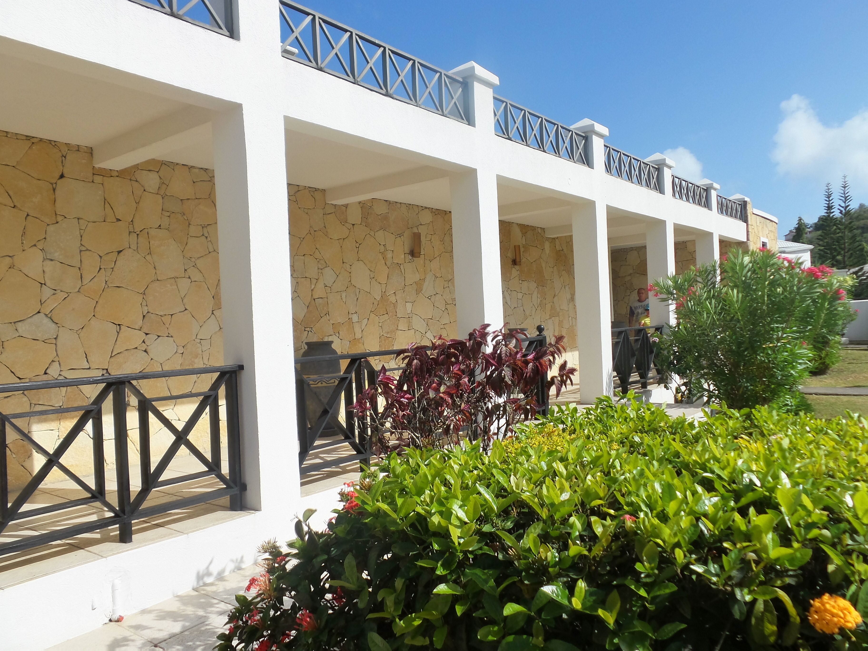 A building with a stone facade, white columns, and a balcony with a metal railing.