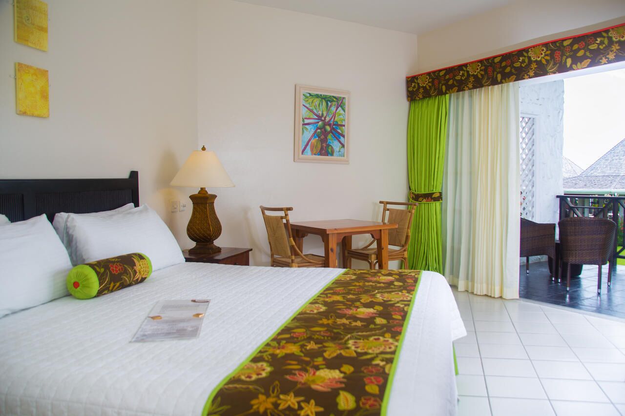 Une chambre d’hôtel équipée d’un lit, d’un bureau, de chaises, d’une lampe et offrant une vue sur l’extérieur.