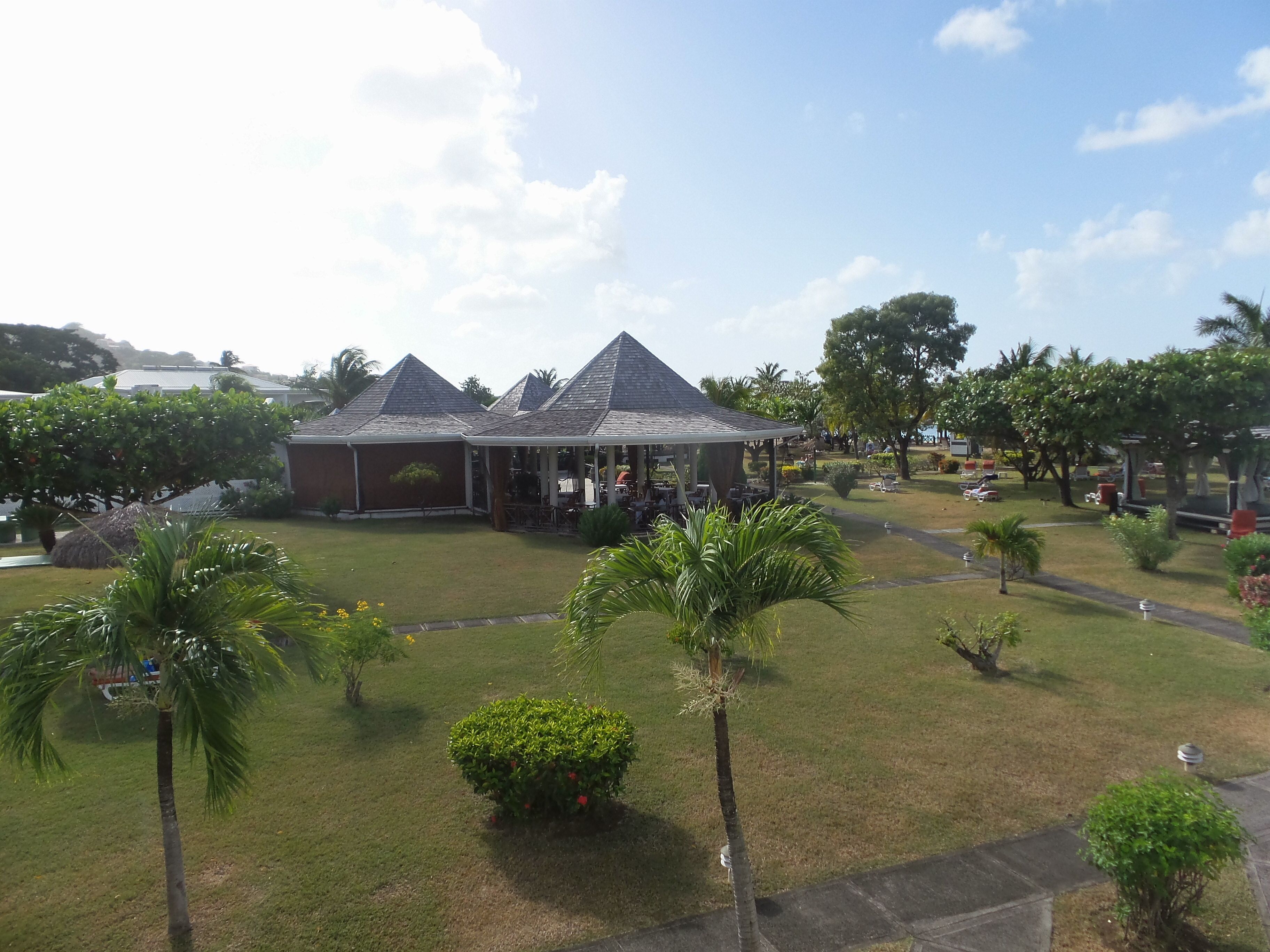 A building with a covered patio area, surrounded by a well-maintained lawn and palm trees.