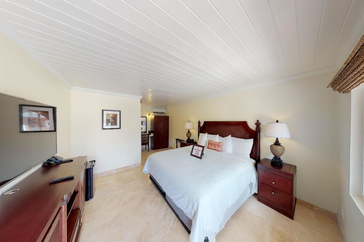 A hotel room with a large bed, a desk with a TV, and a window with a view.