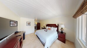 Ein Hotelzimmer mit einem großen Bett, einem Schreibtisch mit Fernseher und einem Fenster mit Blick.