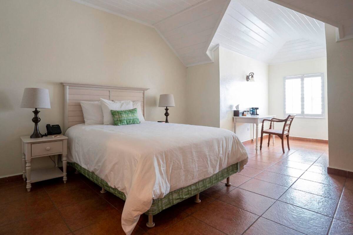 A bedroom with a bed, two bedside tables, a desk, and a chair.