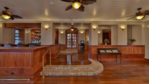 A lobby with wooden reception desk, a tiled floor, and ceiling fans.