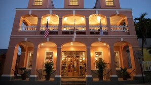 A hotel with a symmetrical facade, multiple balconies, and a central entrance with a glass door.