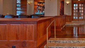 A bar area with wooden seating, a bar counter, and a staircase leading to an upper level.