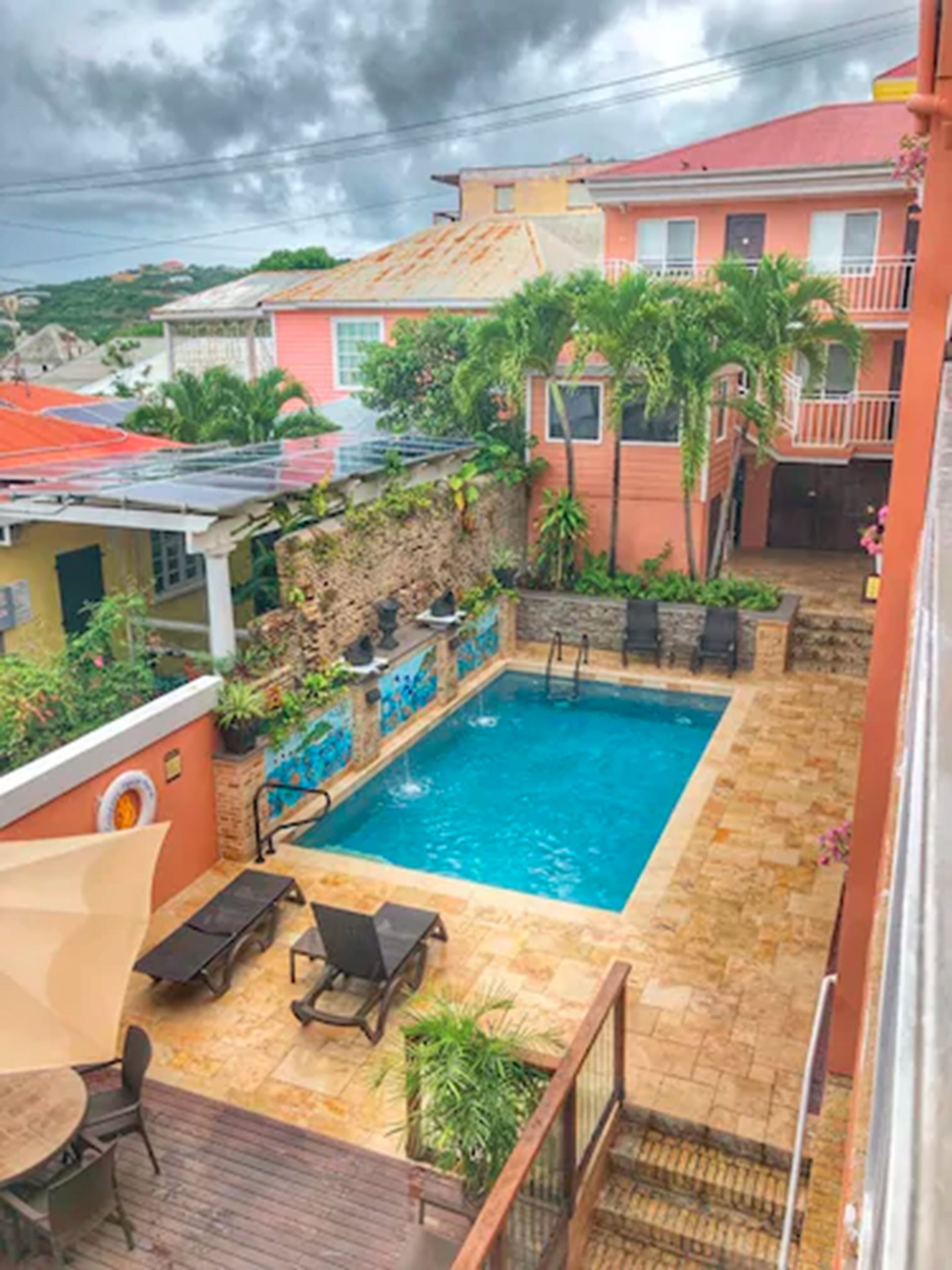 A rooftop swimming pool with a stone deck, lounge chairs, and a small waterfall feature.
