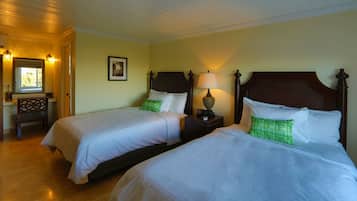 A hotel room with two beds, a nightstand with a lamp, a wooden chair, and a framed picture on the wall.