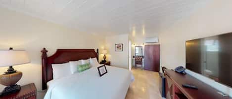 Quarto de hotel com uma cama grande, televisão, escrivaninha e guarda-roupa.