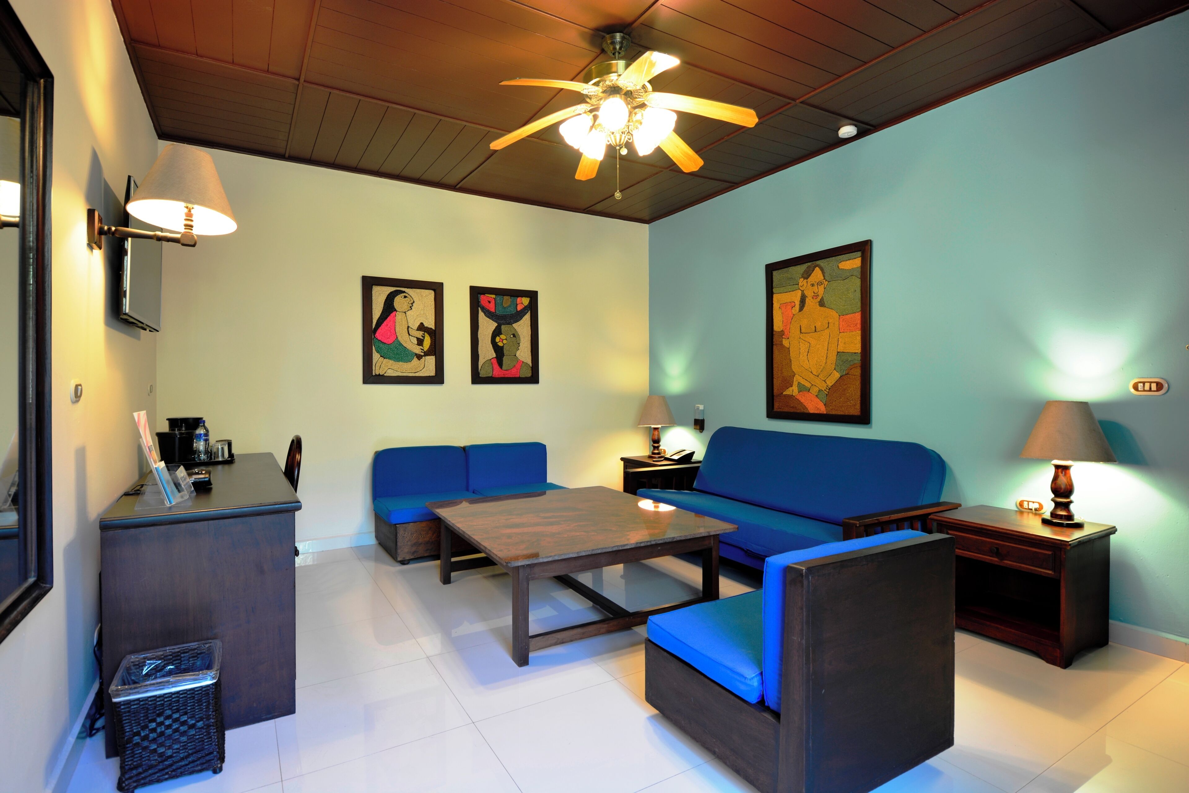 Un salon comprenant un canapé, une table basse, un bureau et un ventilateur de plafond.