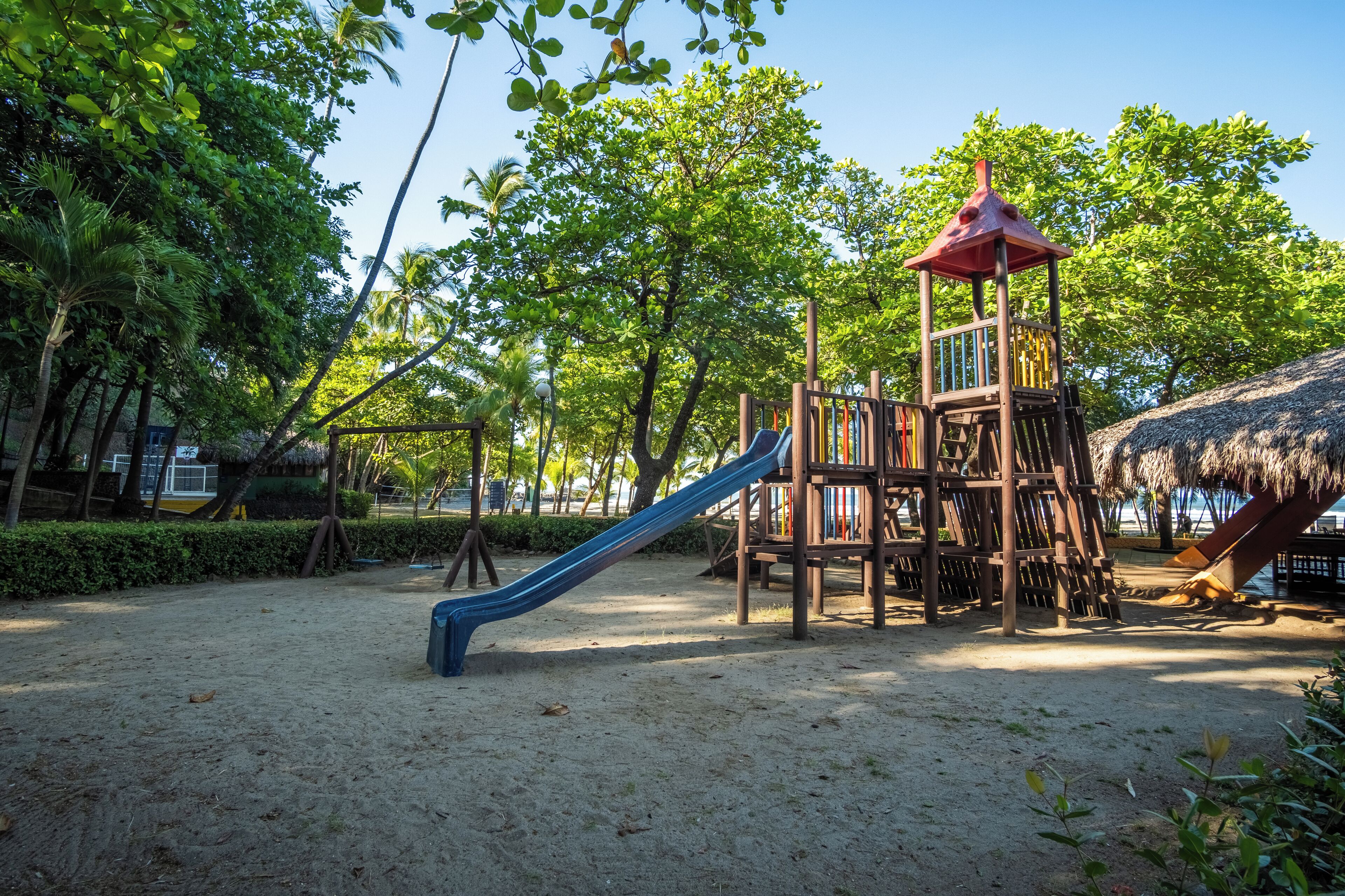 Une aire de jeux avec un toboggan et une structure d’escalade en bois.