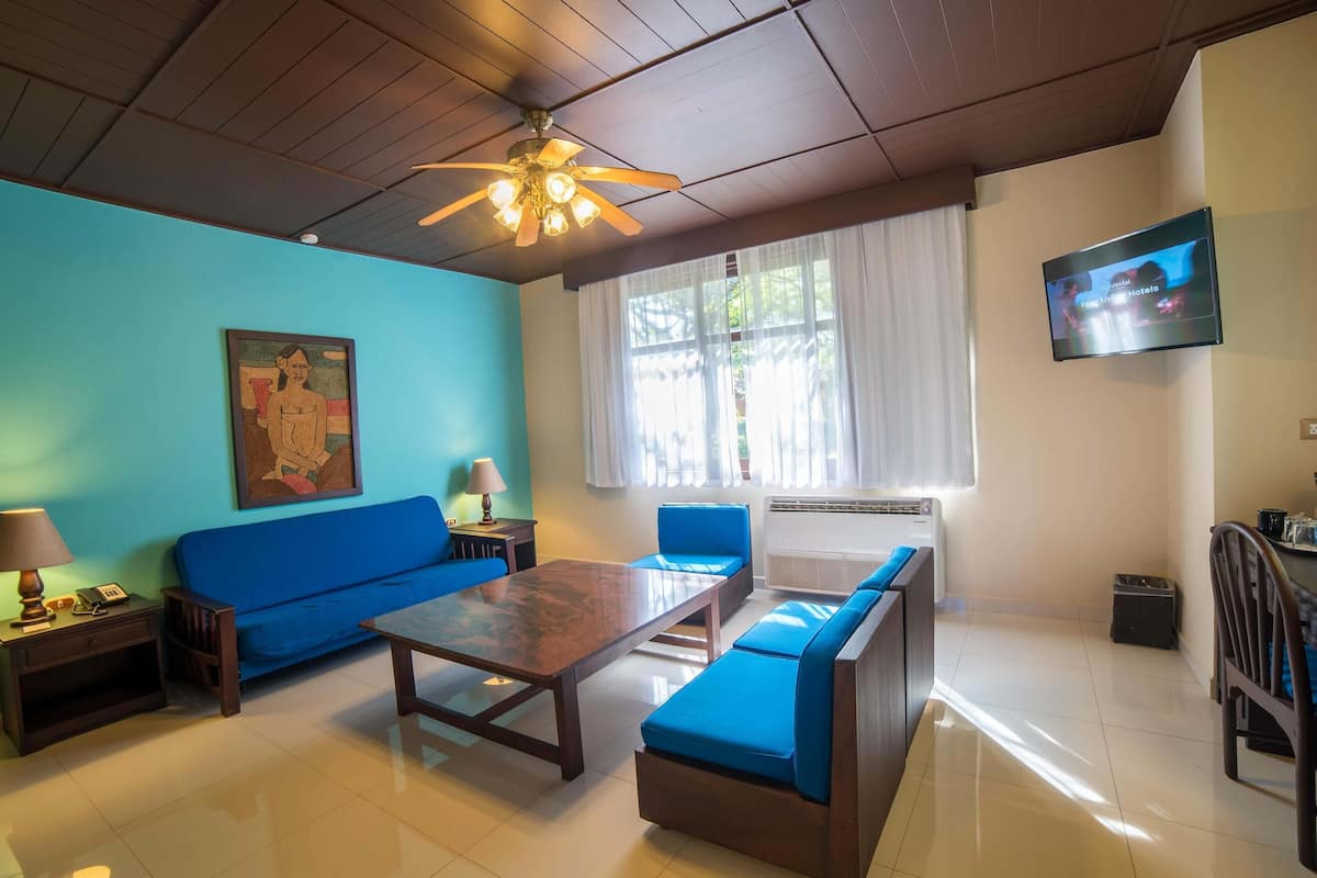 A living room with a blue sofa, a wooden coffee table, and a ceiling fan.