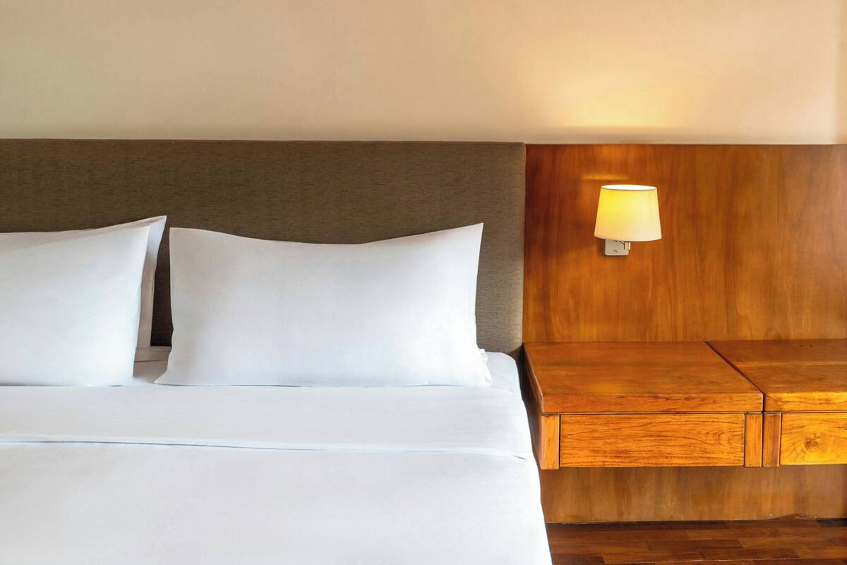 Una cama bien hecha con sábanas blancas y cabecera de madera.