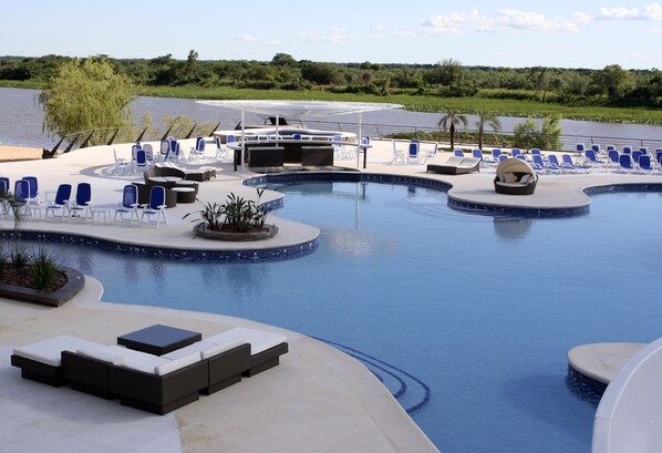 A pool area with lounge chairs, a sunbed, and a small bar area.