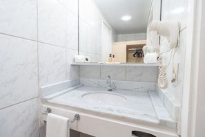 Une salle de bain avec un lavabo en marbre, un porte-serviettes, un sèche-cheveux et un miroir.