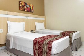 Une chambre d’hôtel avec deux lits, une tête de lit, une table de chevet et un tableau au mur.