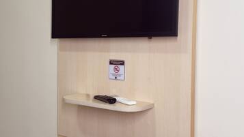 Un televisor montado en la pared sobre una estantería con un control remoto.