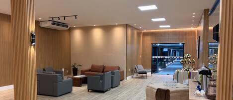 A modern hotel lobby with a seating area, a reception desk, and a view of the entrance.