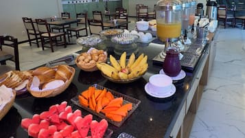 Buffet com diversos alimentos e um dispensador de sucos.