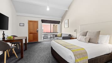 A hotel room with a bed, a desk with a chair, a TV, and a window with a view of the outside.