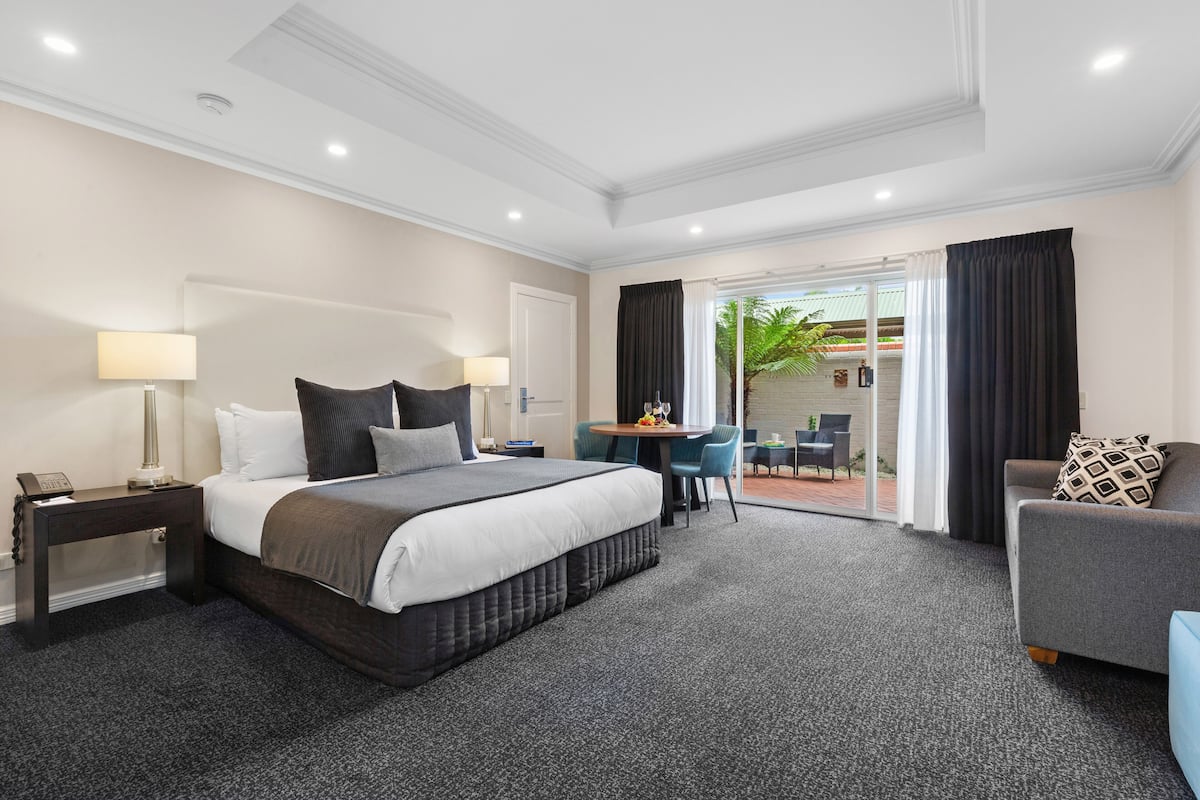 Quarto de hotel com uma cama grande, uma escrivaninha, uma cadeira e um sofá.