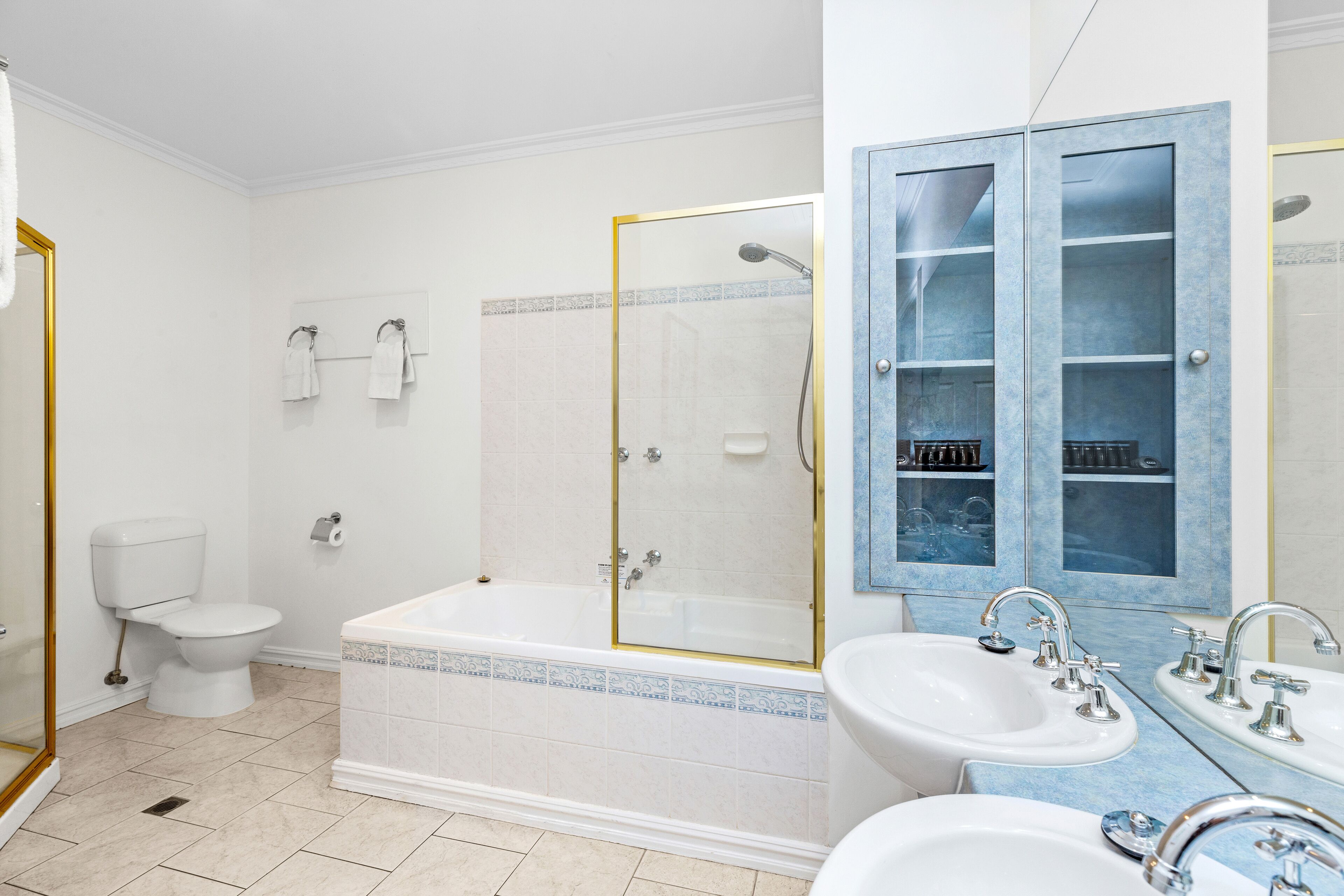 Une salle de bain avec des toilettes, une baignoire et deux lavabos.