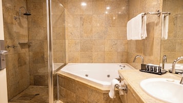 A bathroom with a glass-enclosed shower, a freestanding bathtub, and a vanity with a sink and towel rack.