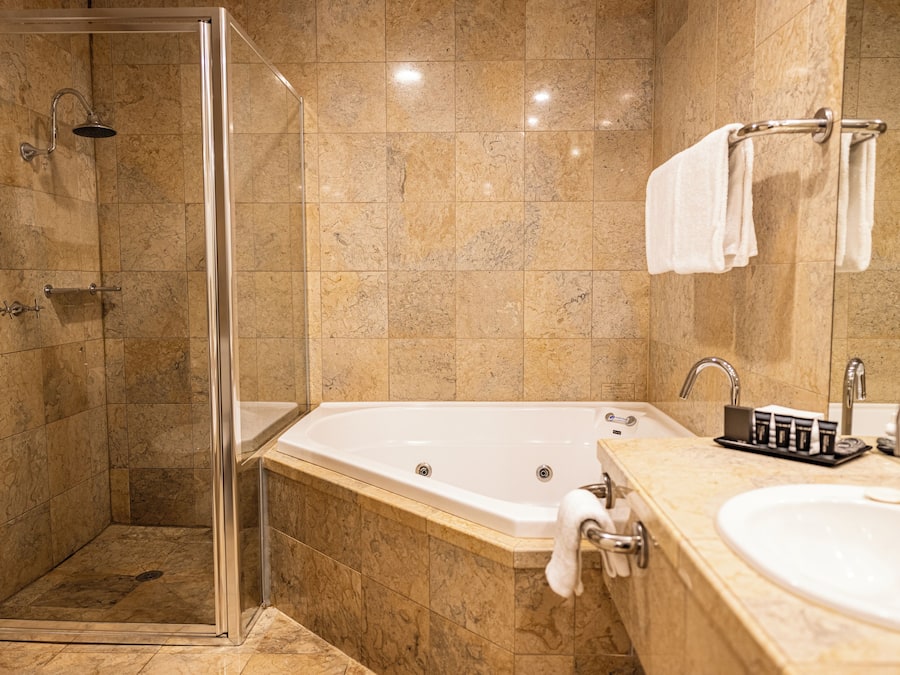 A bathroom with a glass-enclosed shower, a freestanding bathtub, and a vanity with a sink and towel rack.