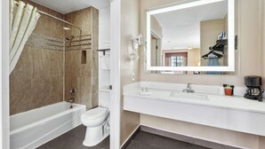 A modern bathroom with a bathtub, toilet, and a large mirror above the sink. - Executive Inn Hotel (Milpitas)