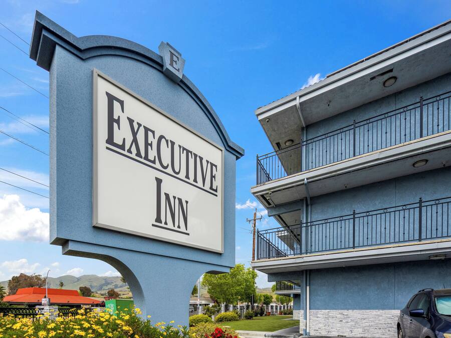 Schild für das Executive Inn mit freiem Blick auf die Außenansicht des Hotels.