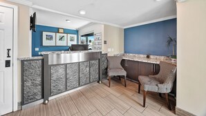 A modern kitchen with a marble island, two patterned chairs, and a blue accent wall. - Executive Inn Hotel (Milpitas)